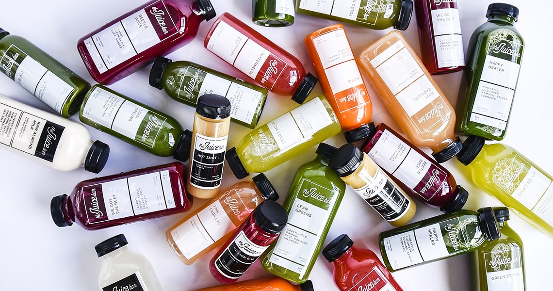 Cold-pressed juices from The Juice Bar in every color, scattered on white
