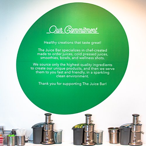 The Our Commitment wall at The Juice Bar above three juicers